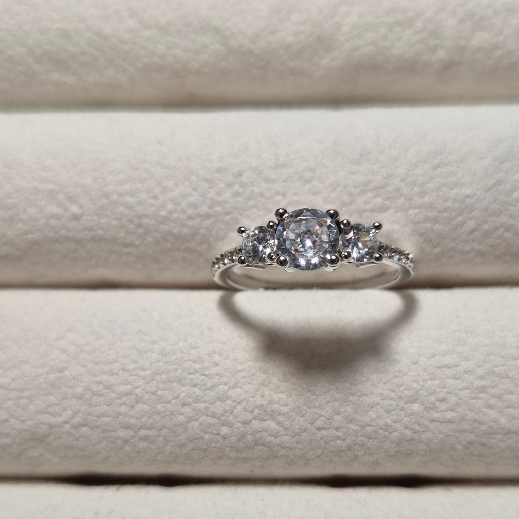 Silver ring with a diamond on a textured beige surface